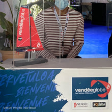Charger l&#39;image dans la galerie, Maquette en résine officielle du Vendée Globe, Imoca au 1/100ème, sous boîte plexi, sur la borne d&#39;accueil du village hospitalités du Vendée Globe 2020
